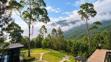 A resort with a glass building, outdoor seating, and a view of a mountainous landscape.