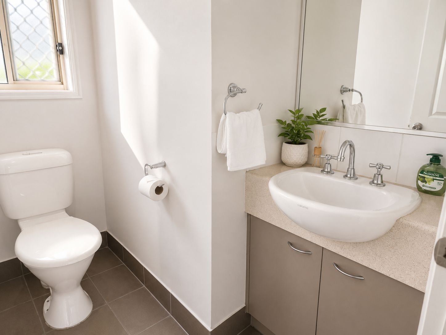 A bathroom with a toilet, a sink, a mirror, and a window.