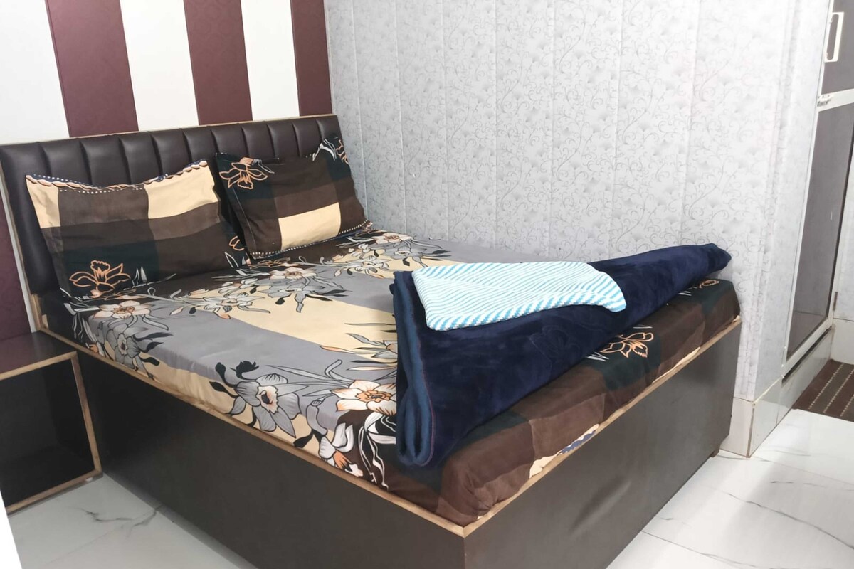 A bed with a floral bedspread, a headboard with a patterned design, and a blue blanket.