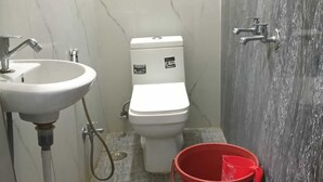 A bathroom with a sink, toilet, and shower area. - Indian Hotel and Restaurant (Bareilly)