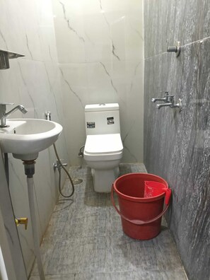 A bathroom with a sink, toilet, and shower area. - Indian Hotel and Restaurant (Bareilly)