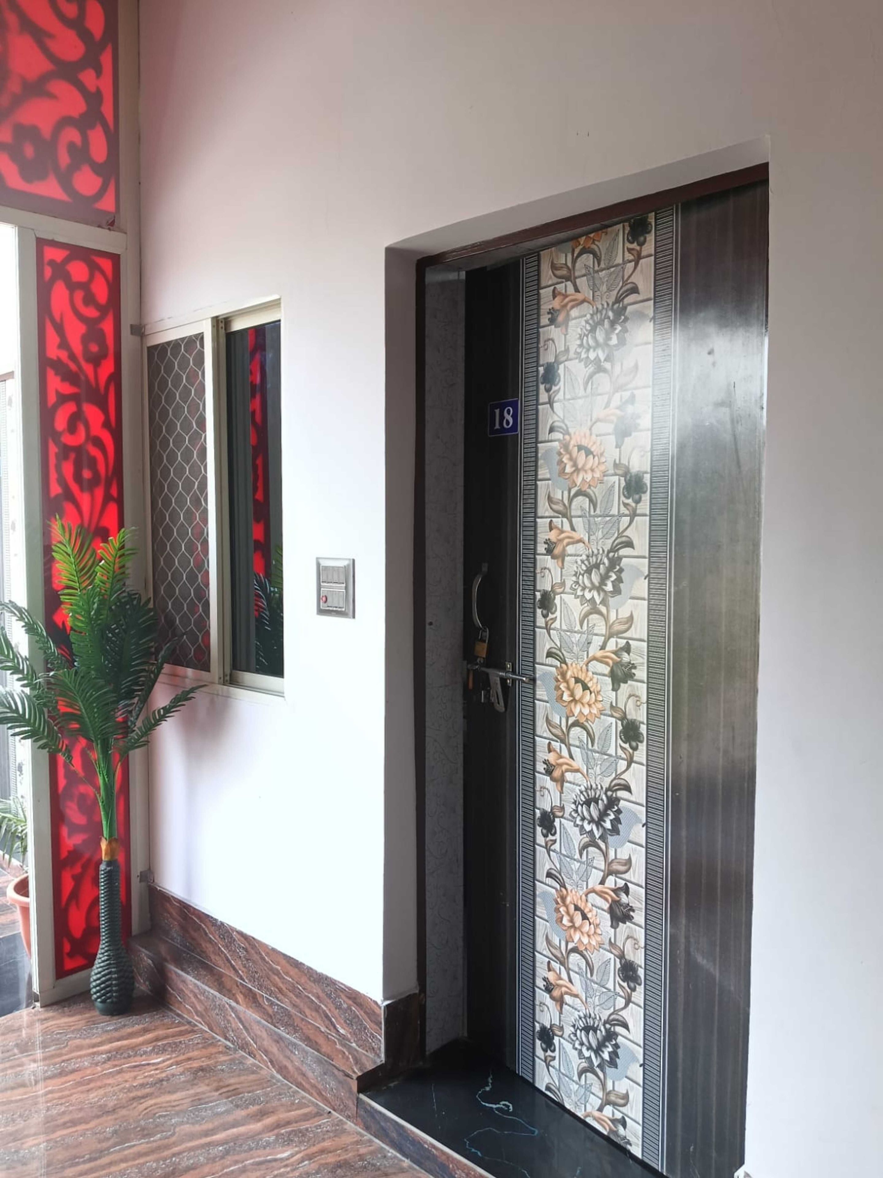 Fachada de un hotel con un muro de azulejos, una puerta con diseño floral y una planta en maceta.