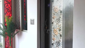 Fachada de un hotel con un muro de azulejos, una puerta con diseño floral y una planta en maceta.
