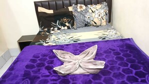 A bed with a purple blanket and a decorative pillow. - Indian Hotel and Restaurant (Bareilly)