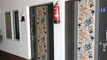 Un pasillo con puertas numeradas 12 y 13, un extintor y un teléfono.