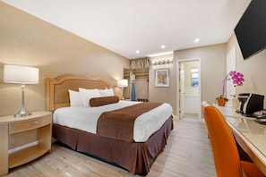 Una habitación de hotel con cama, mesita de noche, silla, escritorio y televisor.