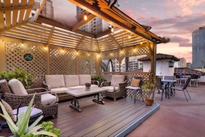 Un patio al aire libre con una pérgola de madera, arreglos de asientos y plantas en macetas.