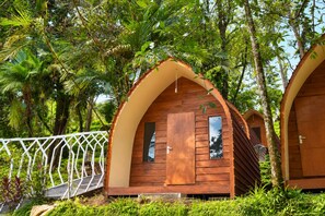 A wooden cabin with an arched roof, surrounded by lush greenery and a white fence. - Tawangmangu Wonderpark (Tawangmangu)