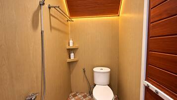 Ein kleines Badezimmer mit Dusche, Toilette und Ablagen für Toilettenartikel.