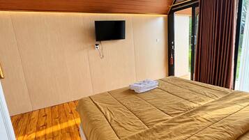 A bedroom with a bed, a television mounted on the wall, and a window with curtains.