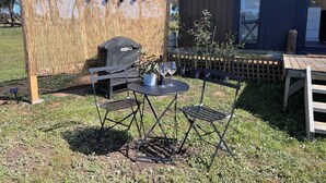 An outdoor seating area with a table and chairs, a grill, and a bamboo screen. - Stringybark by Tiny Away (Rhymney)
