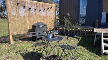 An outdoor seating area with a table and chairs, a grill, and a bamboo screen.
