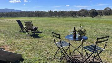 Un espace extérieur aménagé avec une table et des chaises, une bouteille de vin et un verre posé sur la table.