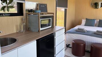 Een moderne slaapkamer met een bed, nachtkastjes, een klein bureau en een magnetron.