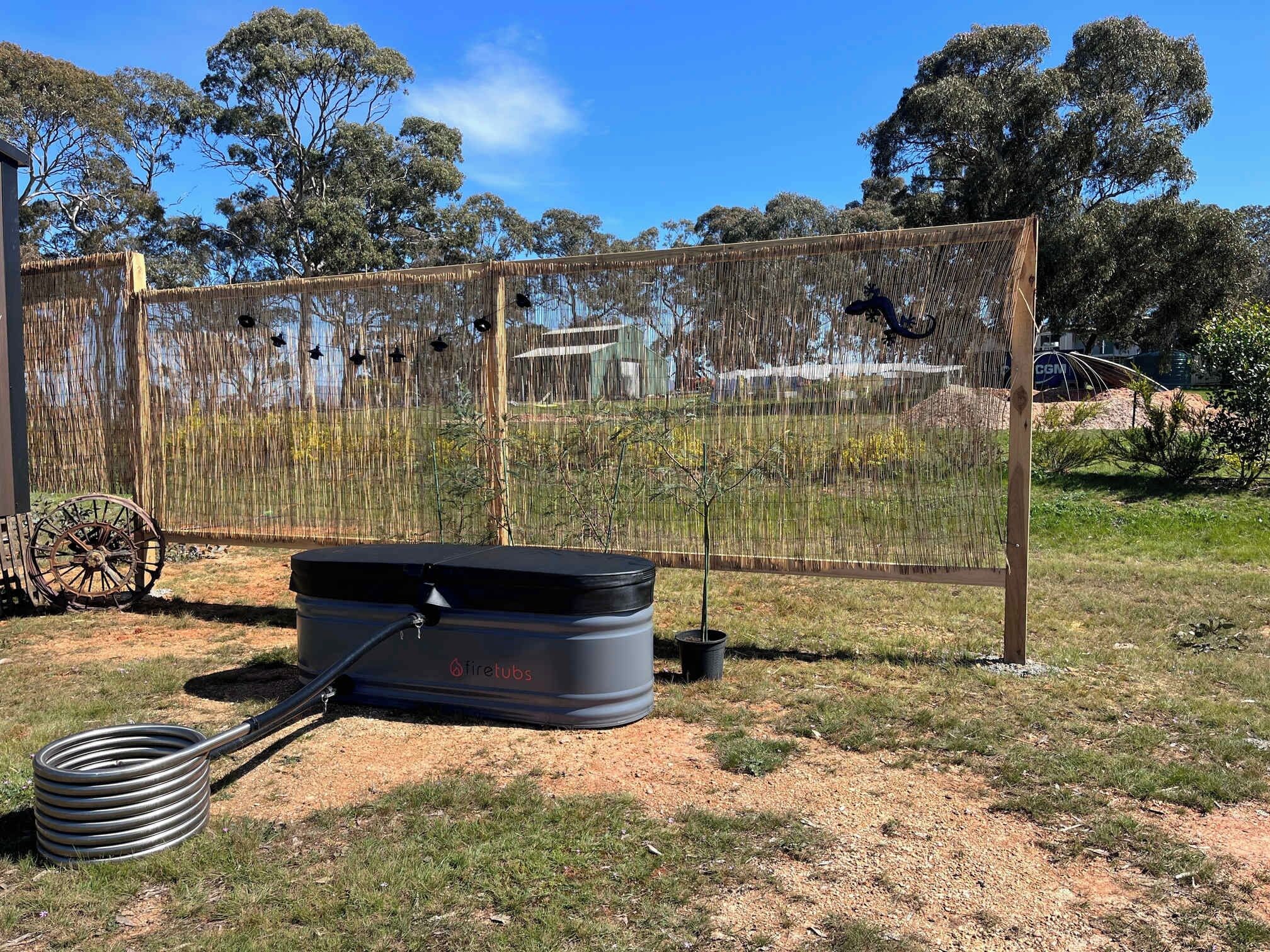 A fenced outdoor area with a fire extinguisher and a hose.