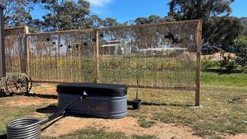 A fenced outdoor area with a fire extinguisher and a hose.