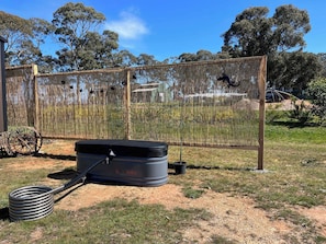 A fenced outdoor area with a fire extinguisher and a hose. - Stringybark by Tiny Away (Rhymney)