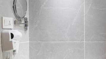 Un baño con lavamanos blanco, espejo, secador de pelo y toallero.