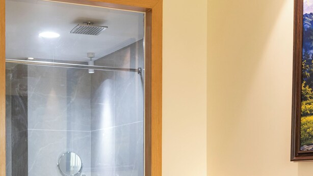 Habitación de hotel con cama, mesita de noche, baño con ducha, lavamanos y espejo.