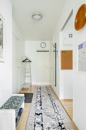 A hallway with a bench, a ladder, a clock, a corkboard, and a map on the wall. - City Station Flat By Lapland Host (Rovaniemi)