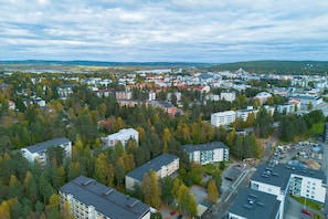 An aerial view of a residential area with multiple apartment buildings, surrounded by dense trees and a distant view of a bridge. - City Station Flat By Lapland Host (Rovaniemi)