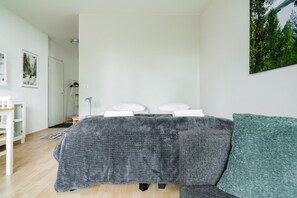 A bedroom with a bed, pillows, a bedside table, a lamp, and a green cushion. - City Station Flat By Lapland Host (Rovaniemi)