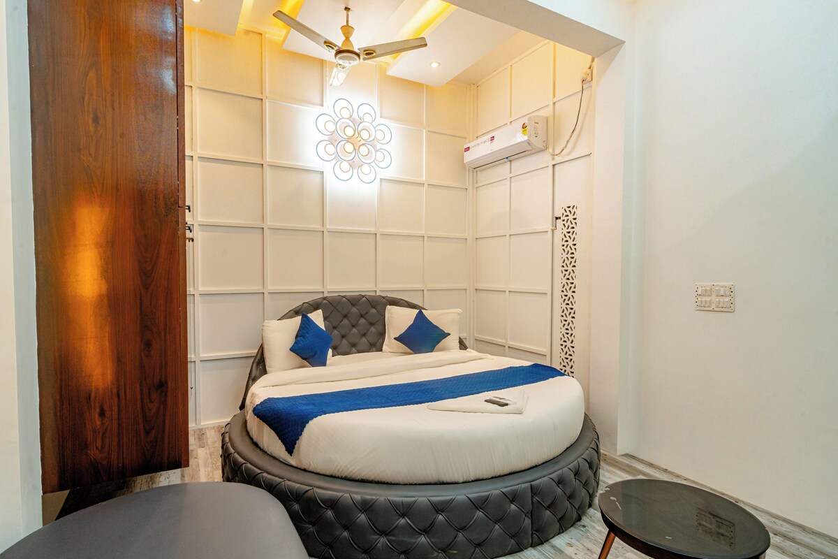 Un dormitorio con cama, ventilador de techo, aire acondicionado y una pequeña mesa.