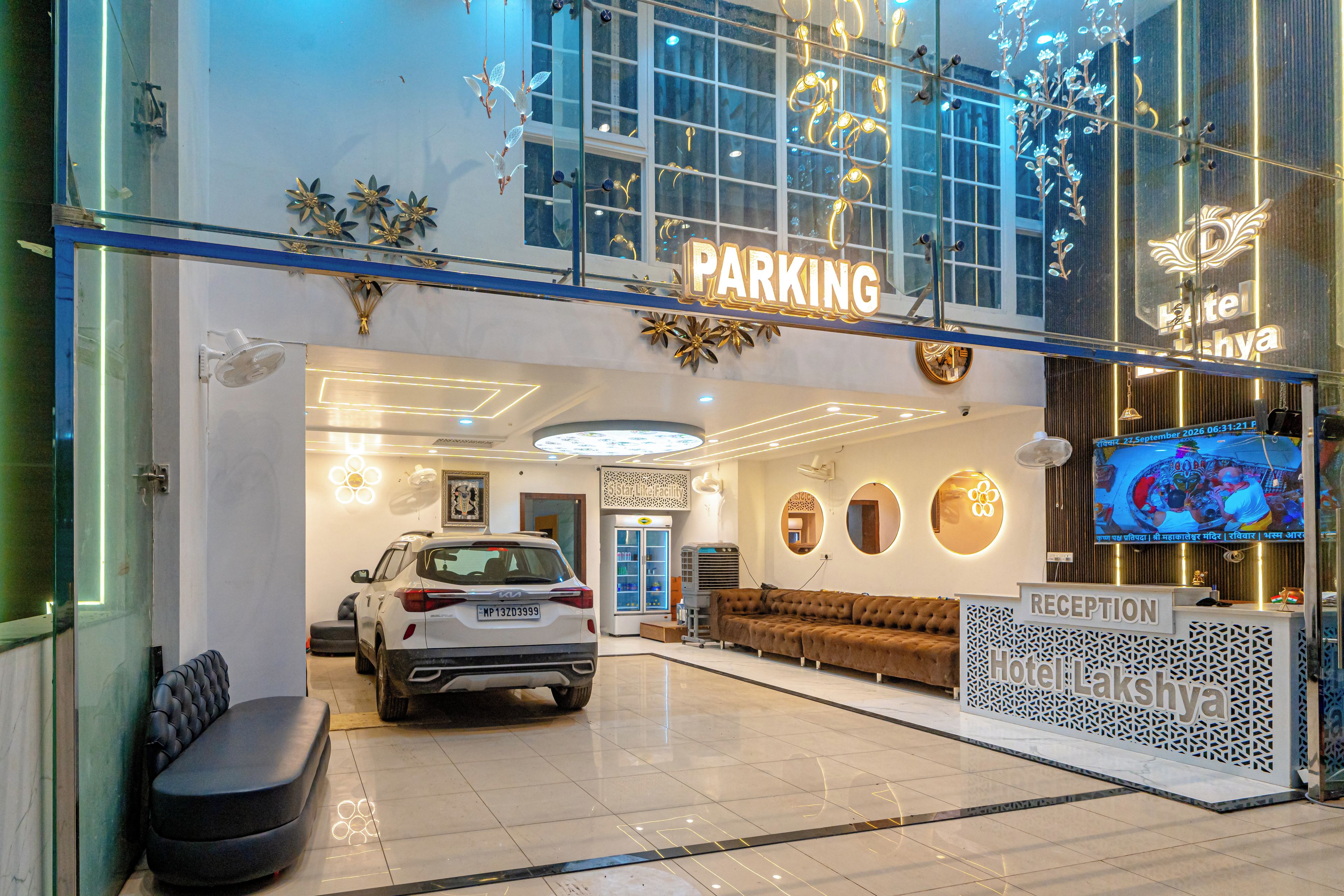 Zona de recepción de hotel con cartel de estacionamiento, mostrador de recepción y pantalla de televisión.