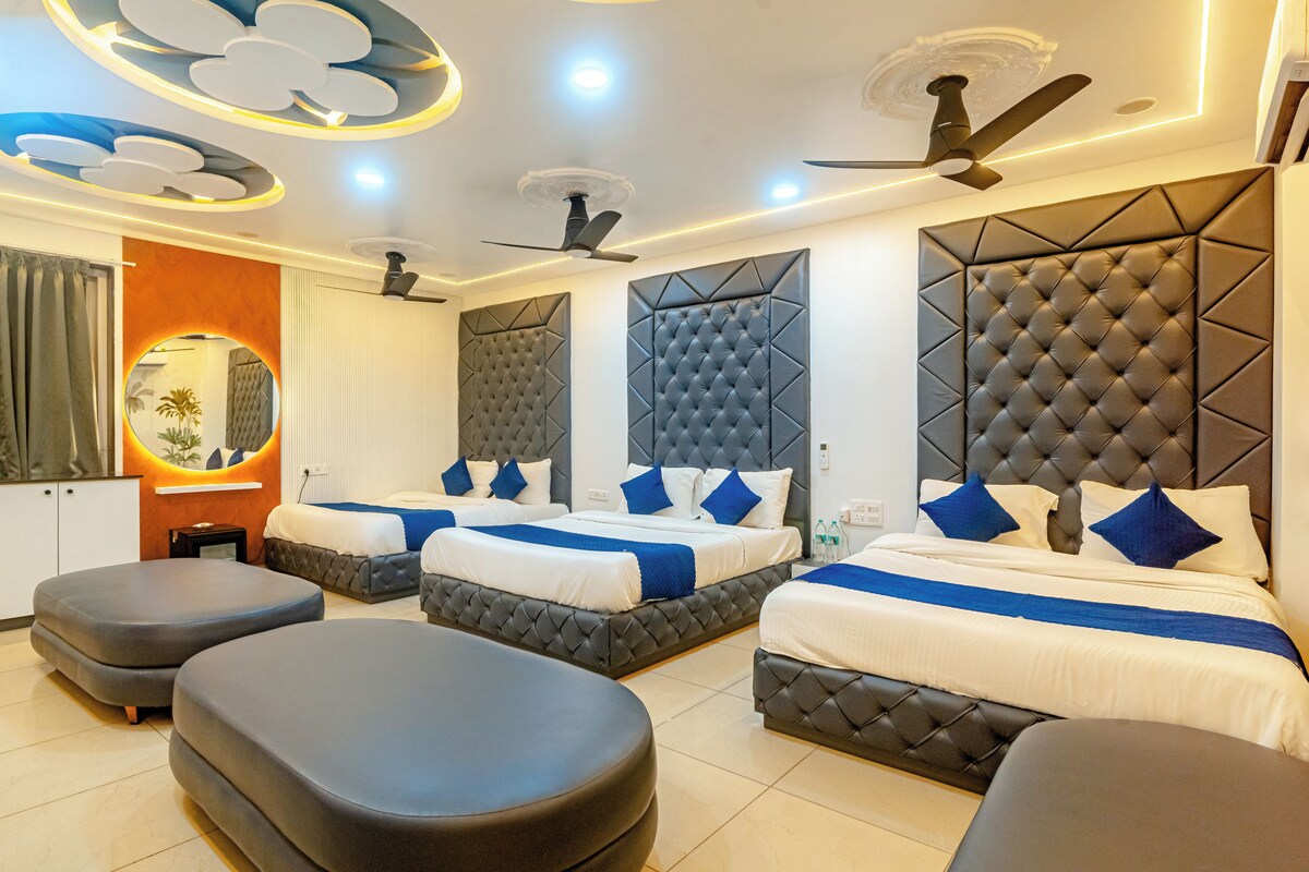 Habitación de hotel con tres camas, ventilador de techo y diseño moderno.