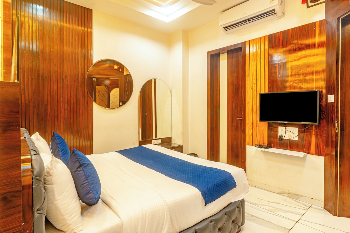 Una habitación de hotel con una cama, un televisor montado en la pared y un ventilador de techo.
