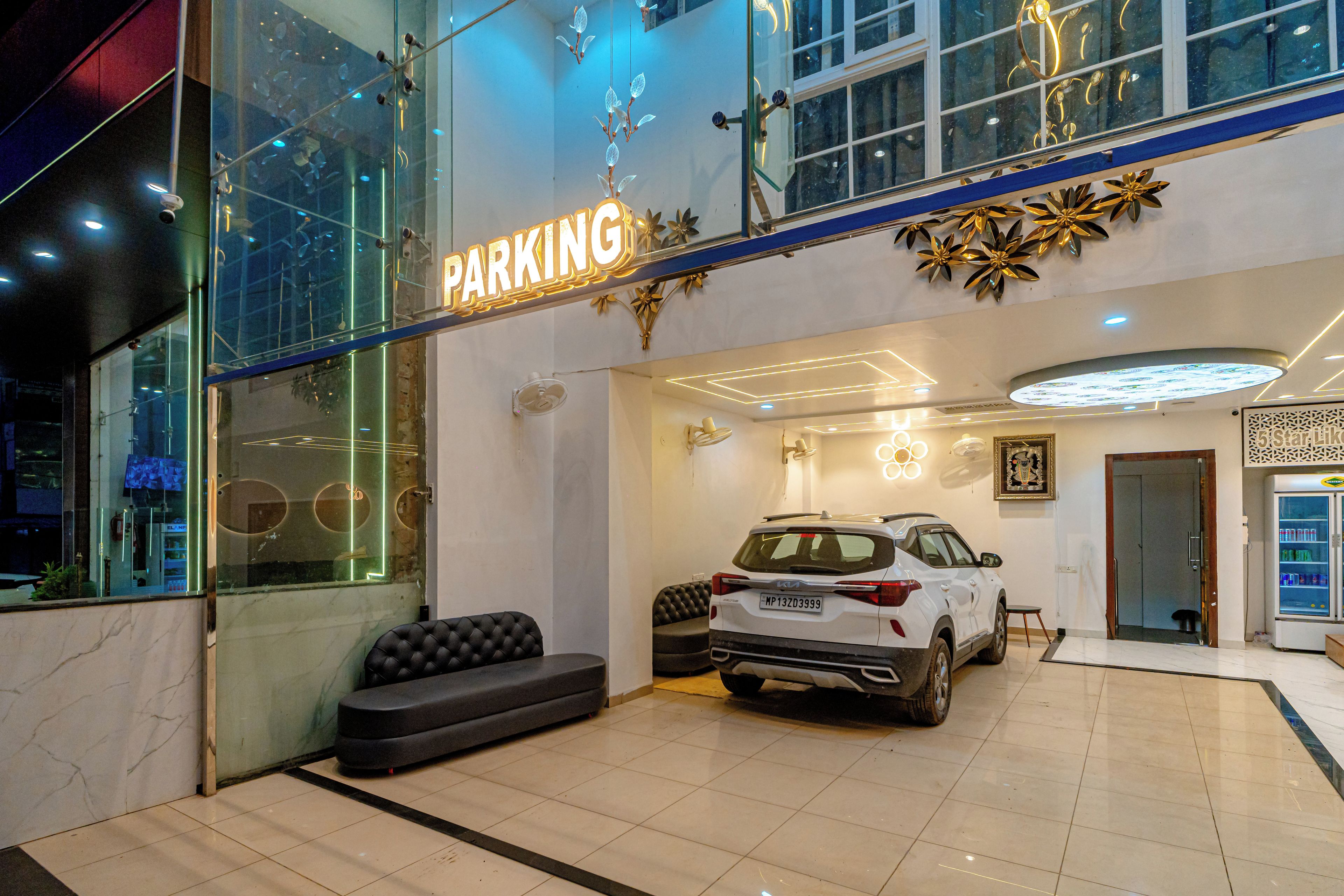 A modern building with a 'PARKING' sign, a white SUV, and a seating area with a black sofa.