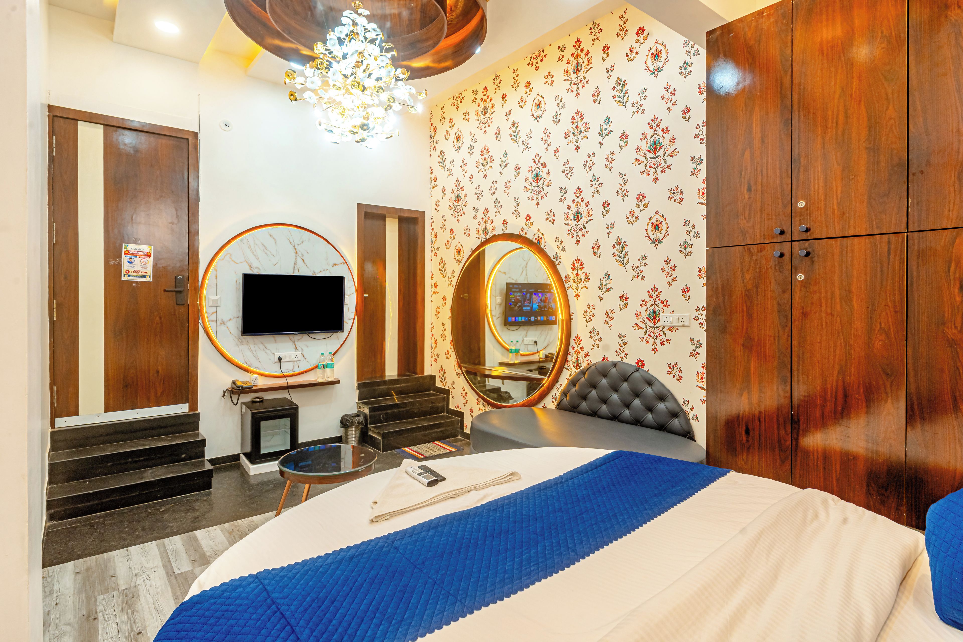 Ein Hotelzimmer mit einem großen Bett, einem Fernseher, einem Spiegel, einem Kleiderschrank und einer Deckenleuchte.