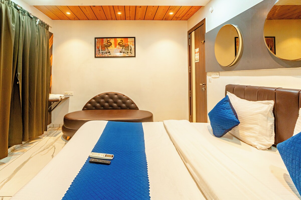 Una habitación de hotel con una cama, una silla, una mesita de noche, un espejo y un cuadro en la pared.
