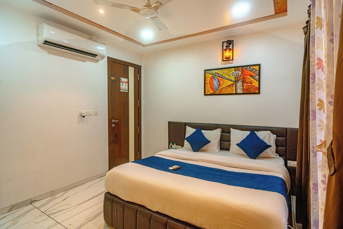 Una habitación de hotel con una cama, un ventilador de techo, aire acondicionado, un cuadro en la pared y una puerta con un cartel.