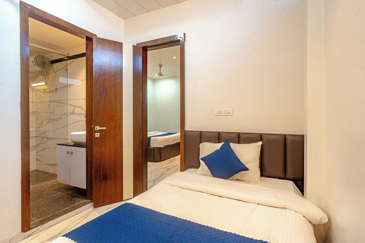 Un dormitorio con cama, mesita de noche, espejo y baño privado con ducha y lavabo.