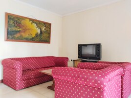 Una sala de estar con un sofá rojo, un televisor y un cuadro en la pared.