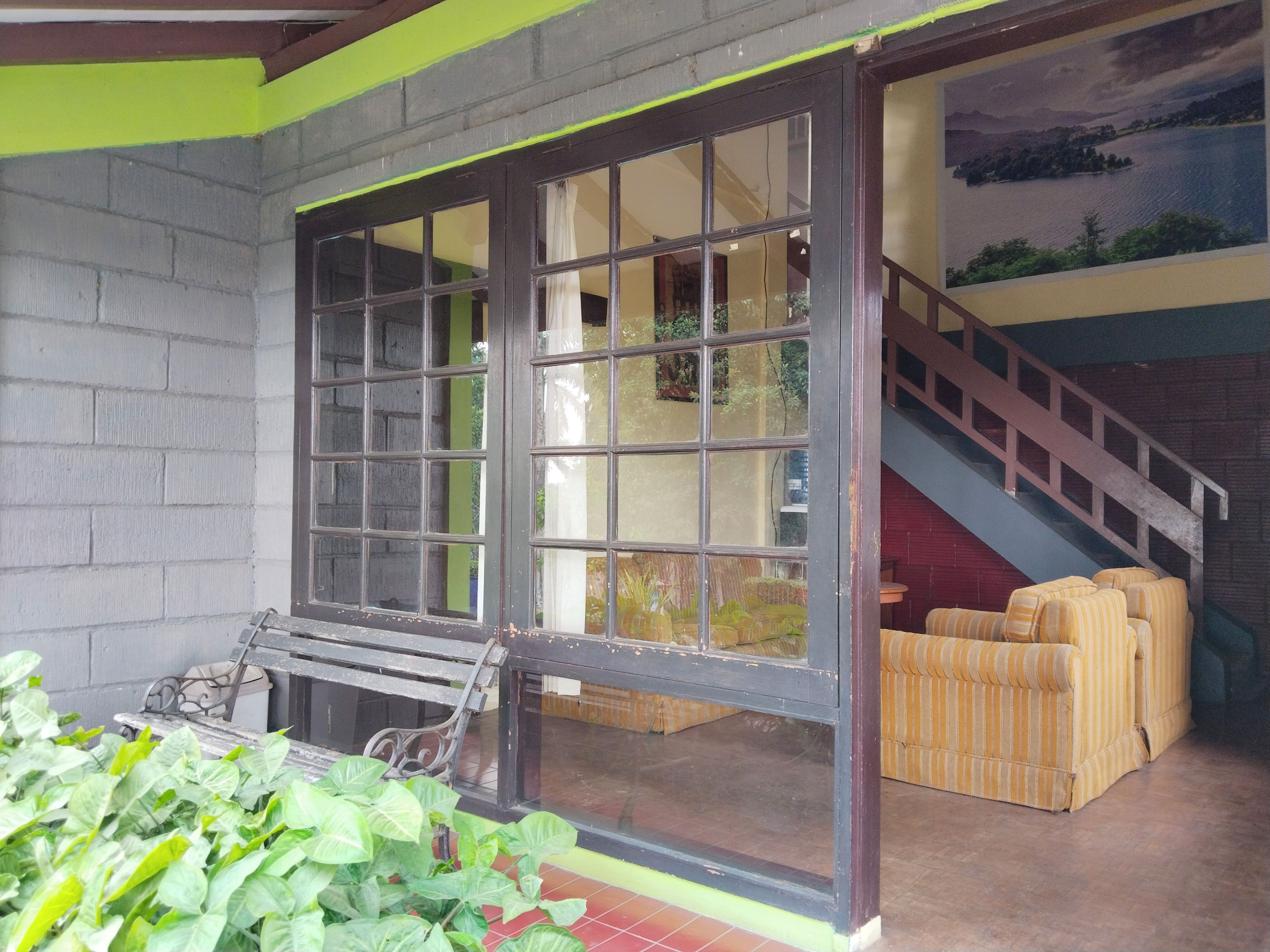 A room with a large window, a staircase, and a seating area with striped cushions.