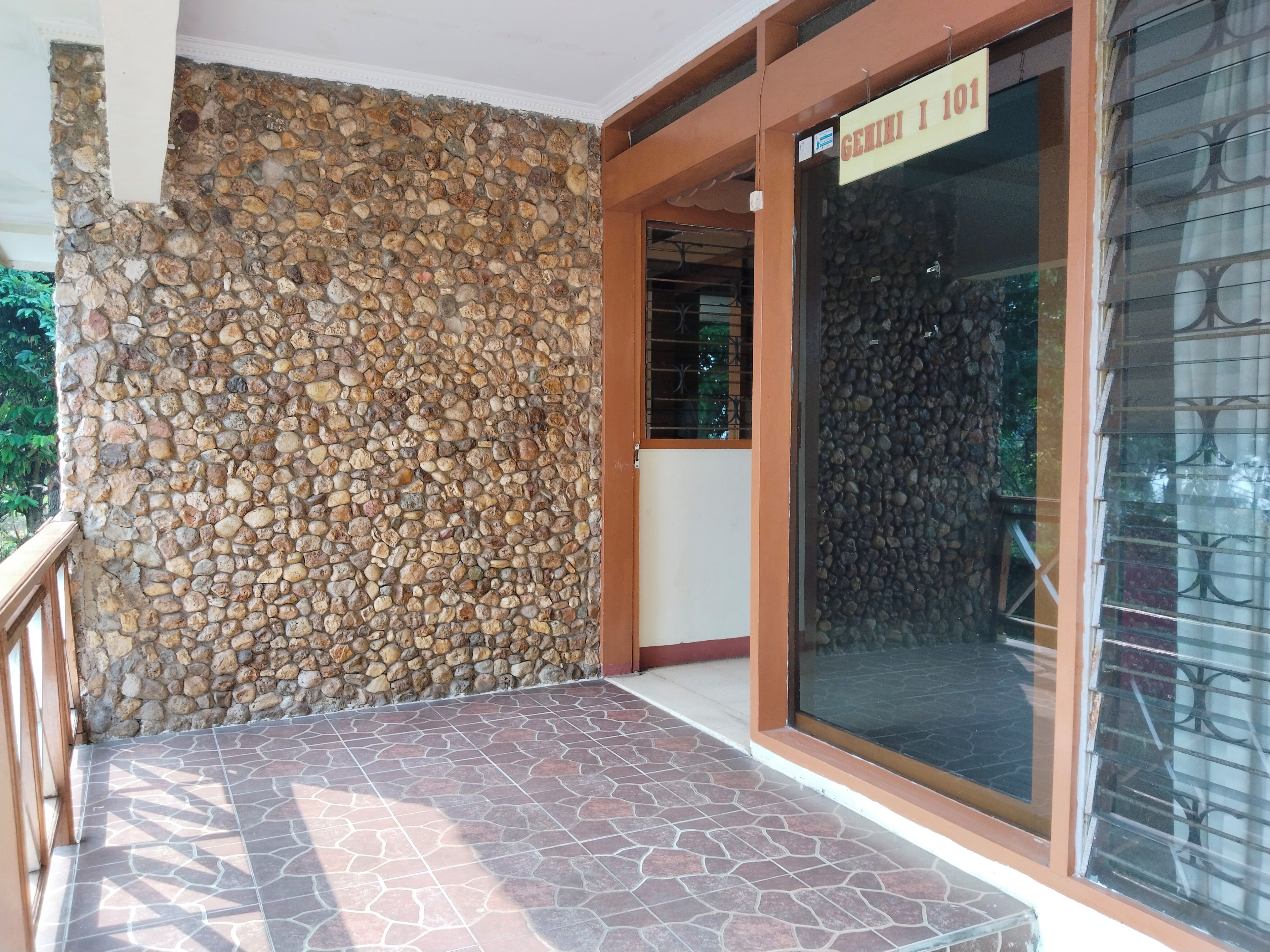 A stone wall and a glass door with a sign above it.