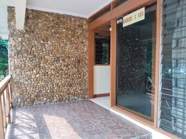 Una pared de piedra y una puerta de cristal con un cartel encima.