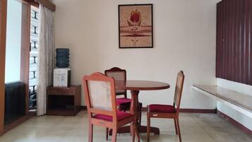 Un comedor con una mesa redonda y cuatro sillas, un dispensador de agua y una obra de arte enmarcada en la pared.