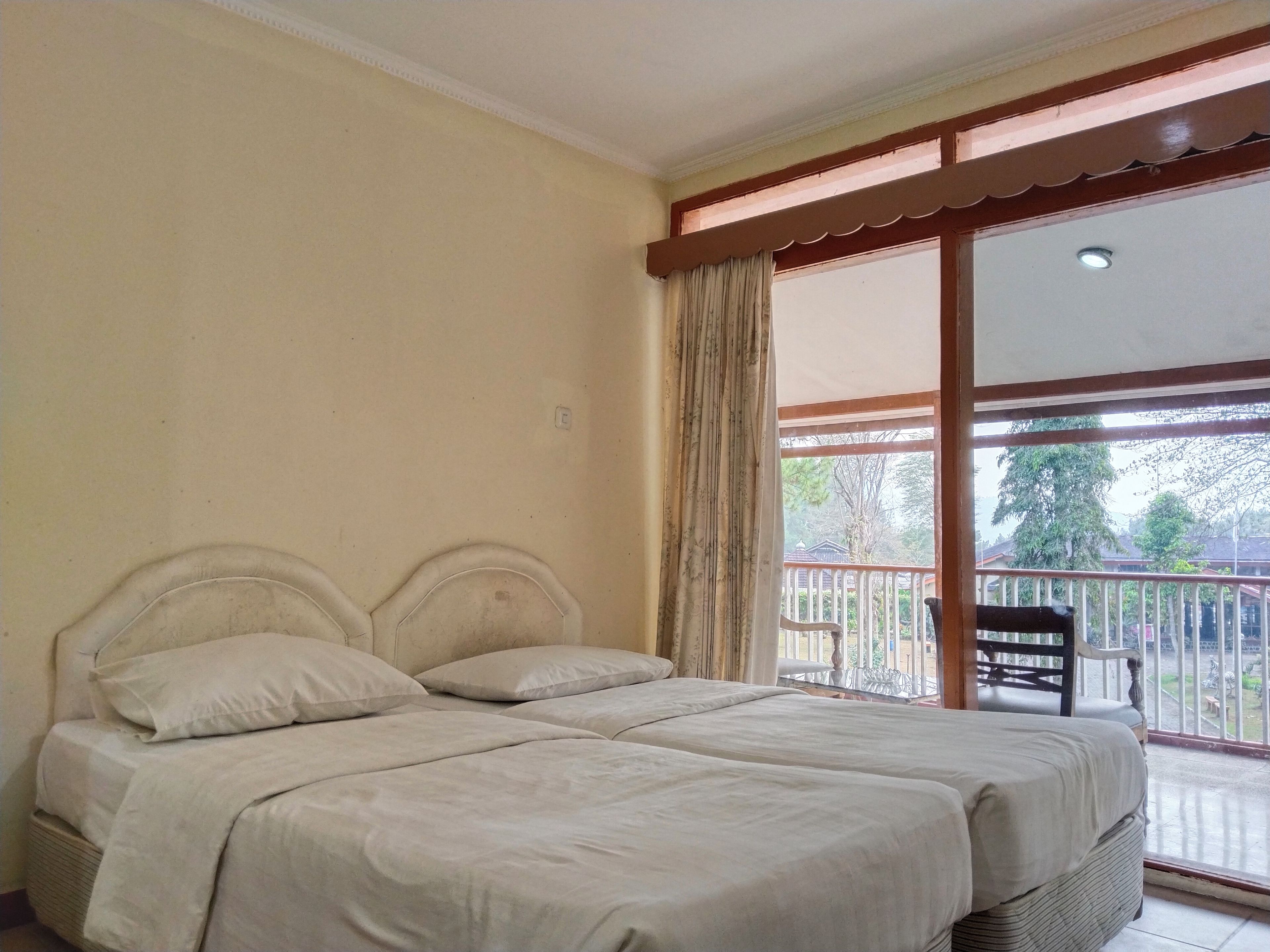 Una habitación con una cama, una ventana con cortinas y vistas a un balcón.