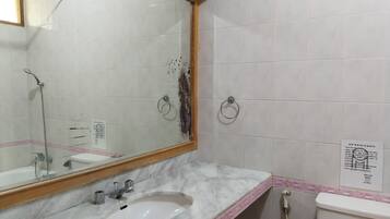 A bathroom with a sink, mirror, and towel rings.