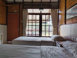 Una habitación con dos camas, techo de madera, ventana con cortinas y una puerta.