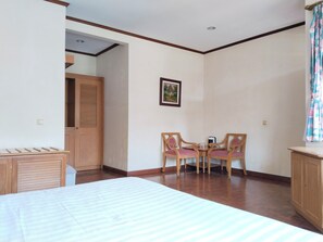 Una habitación con una cama, un armario de madera, una mesita con sillas y un cuadro en la pared.