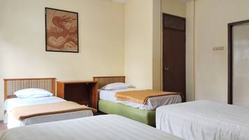A room with three beds arranged in a row, a wooden headboard, a wall-mounted artwork, and a door with a handle.