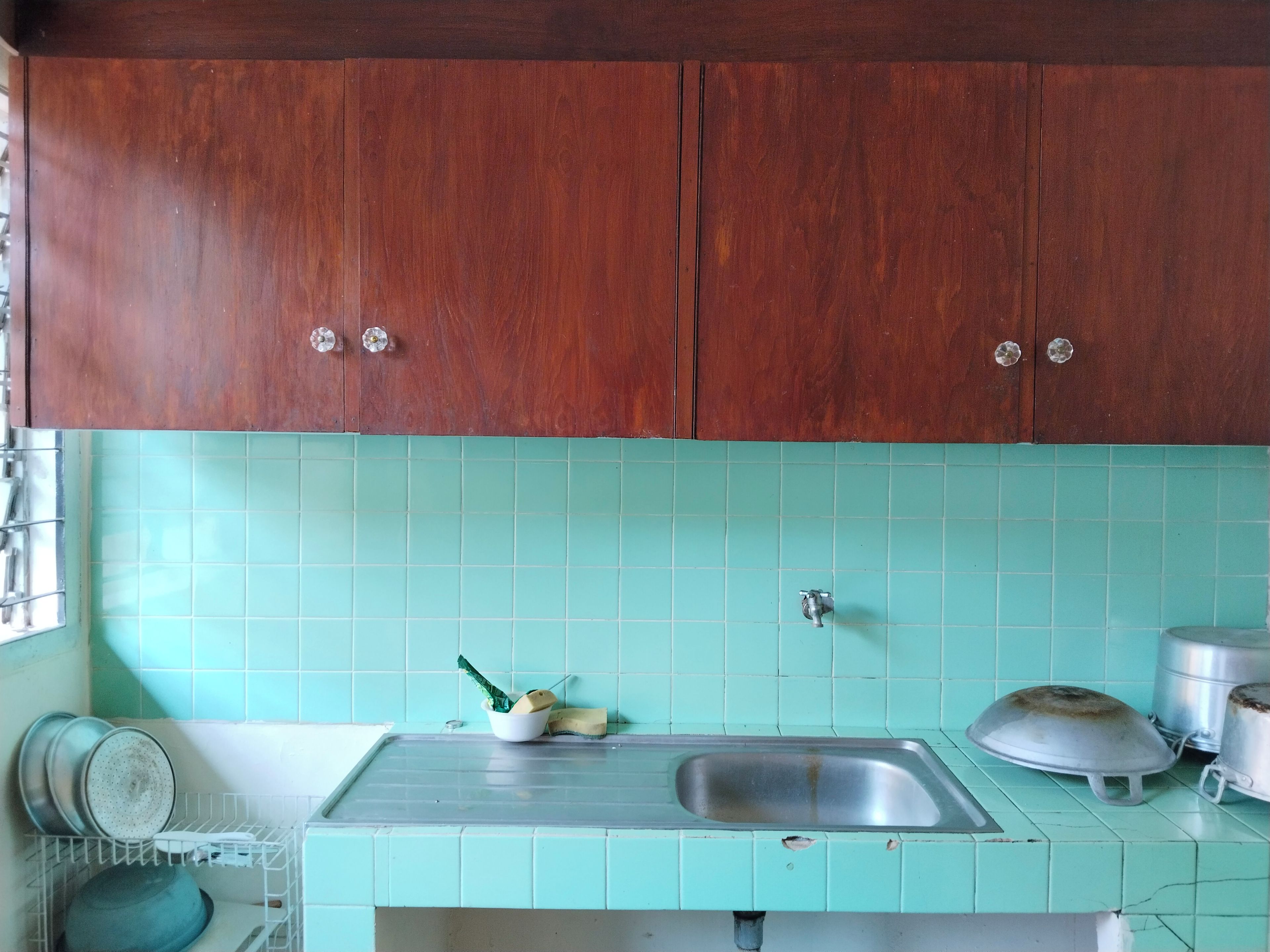 A kitchen with wooden cabinets, a sink, and a tiled backsplash.