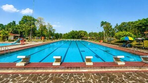 A large outdoor swimming pool with multiple lanes, surrounded by a stone deck and greenery. - Megamendung Permai Hotel & Resort (Kabupaten Bogor)