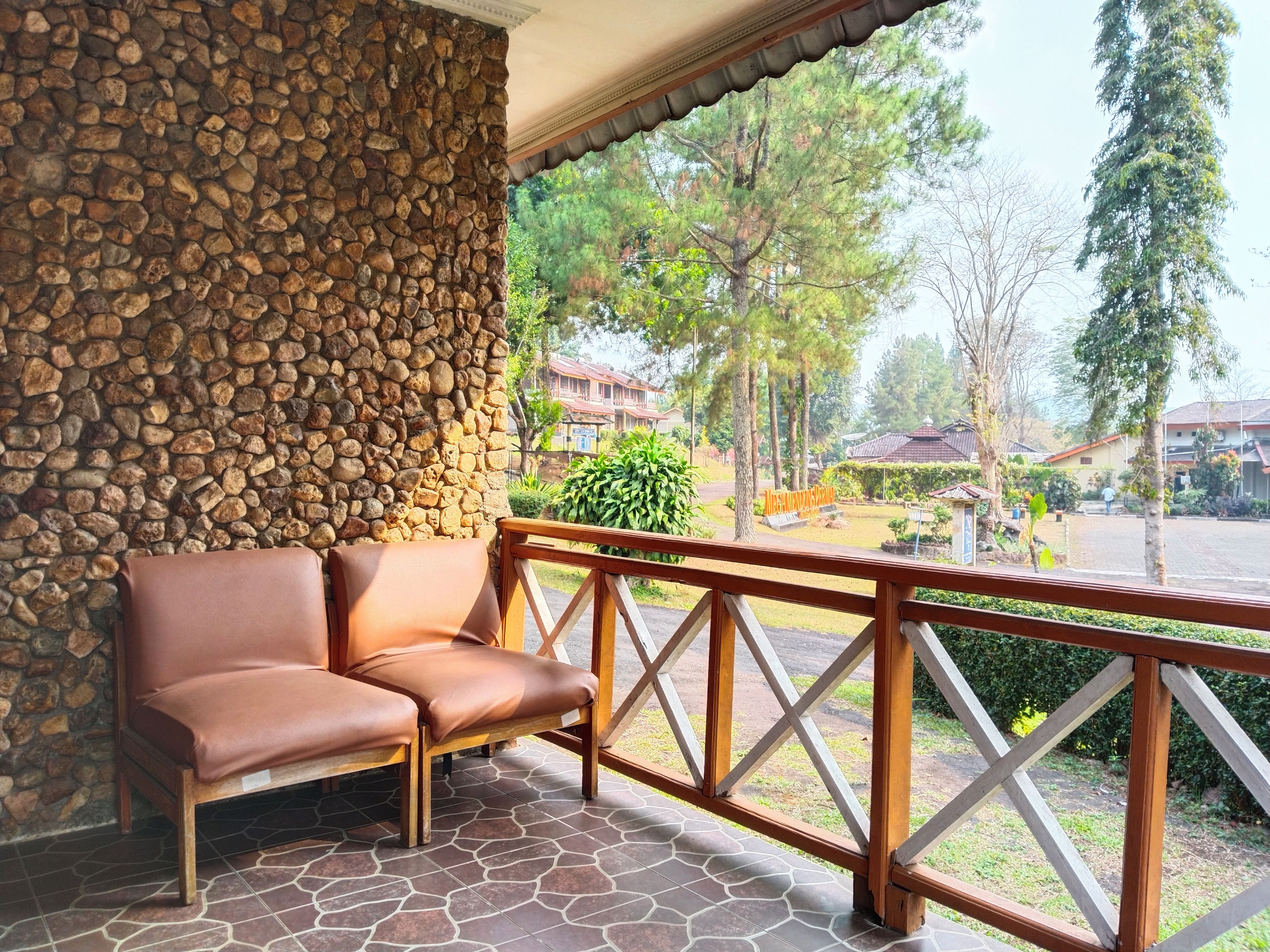 A stone wall, a wooden bench, and a view of a residential area with houses and trees.