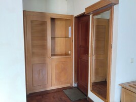 Un armario de madera con puerta espejada y un estante pequeño.