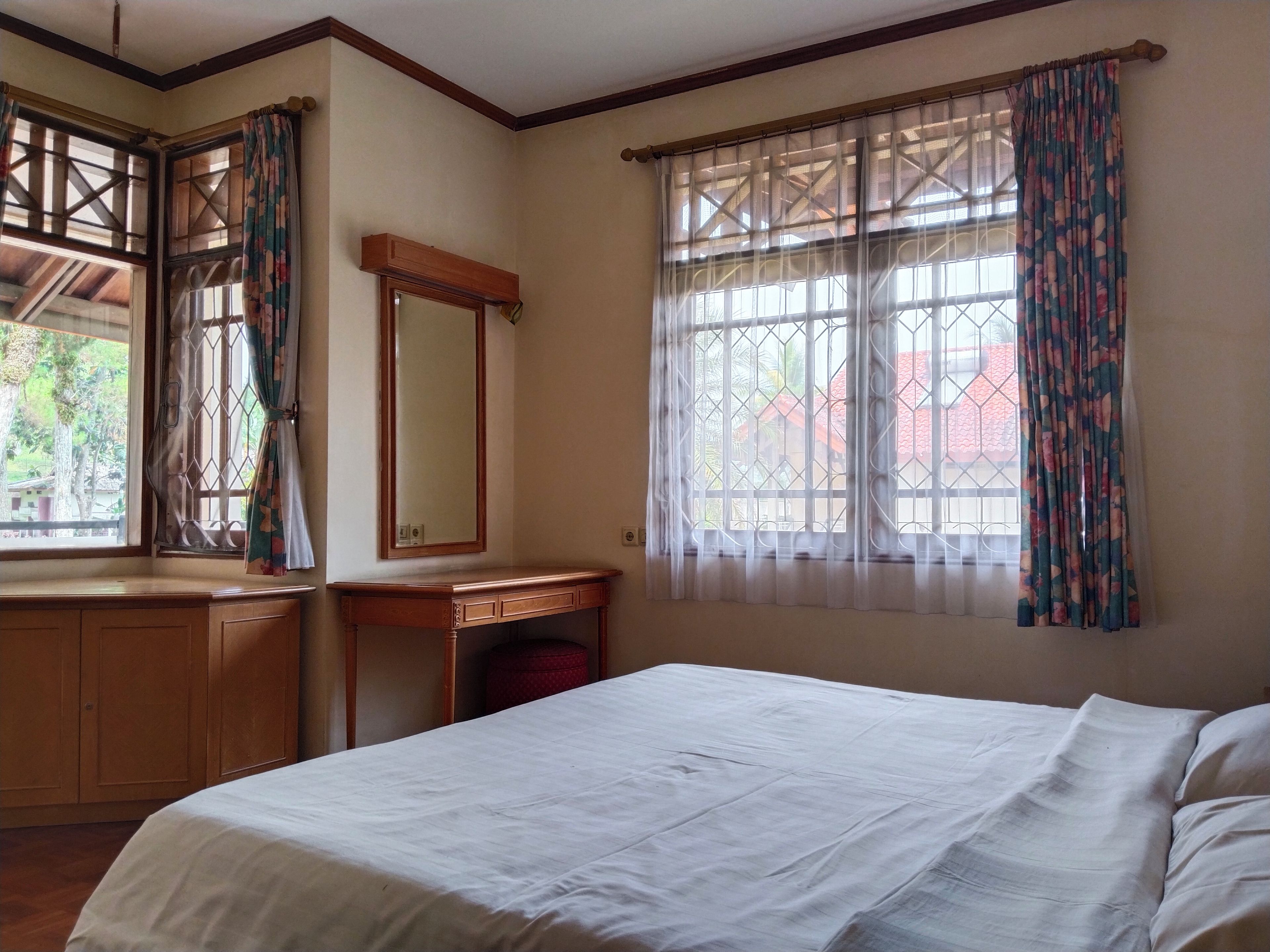 Un dormitorio con cama, cómoda de madera, una mesita y un espejo.